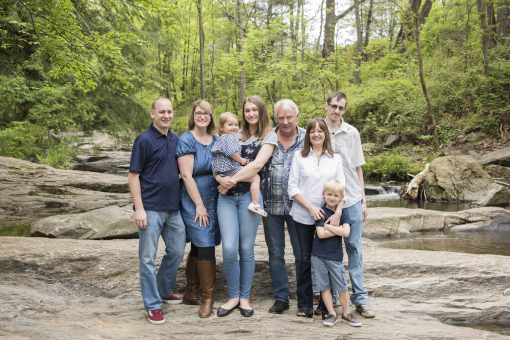 extended family portrait standing on rock in creek during photo shoot in Asheville NC