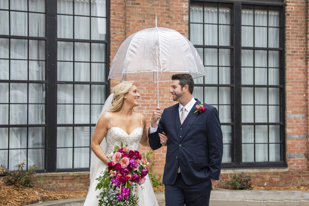 couple walking under umbrella during wedding photos