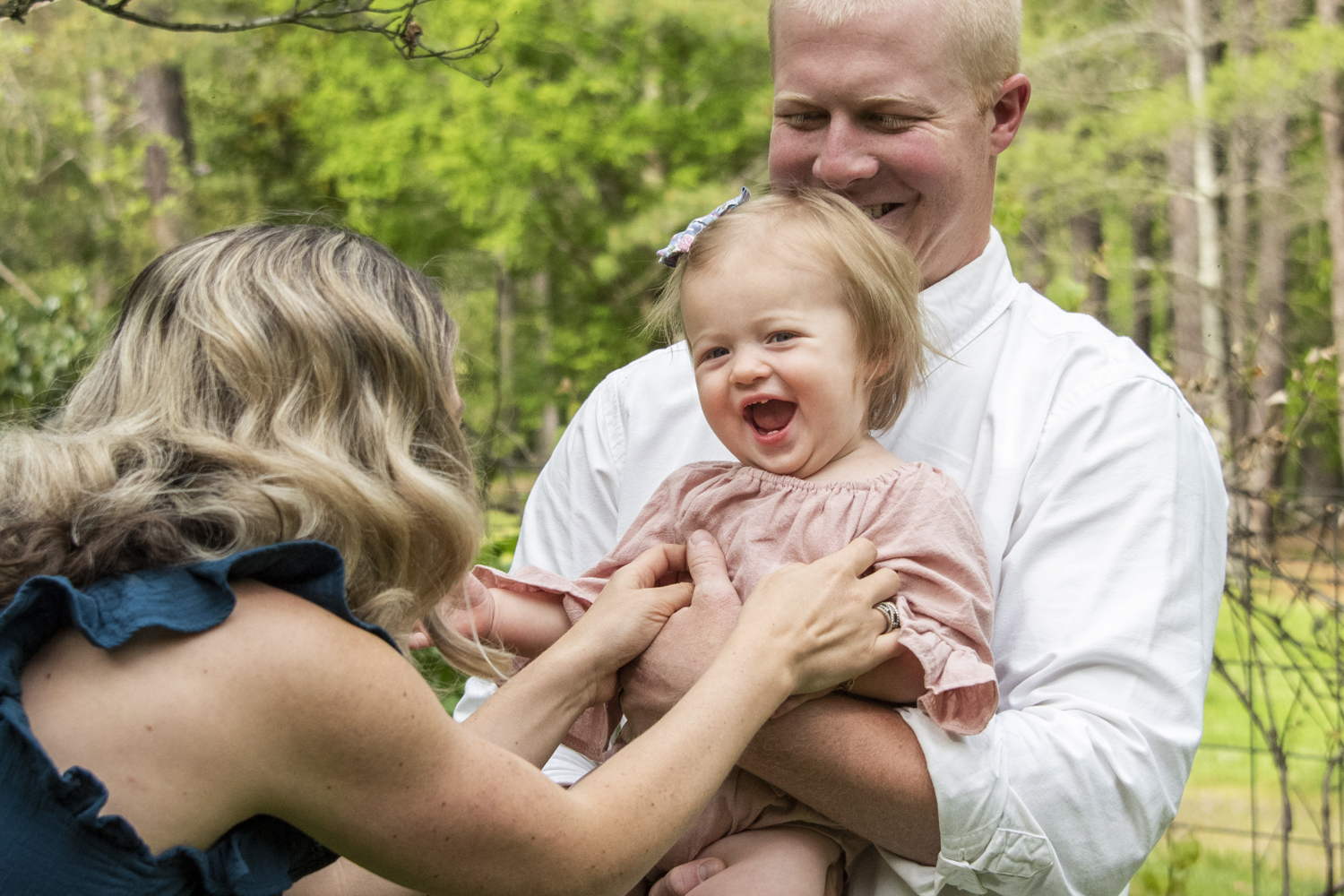 One year old girl giggling with parents in Asheville