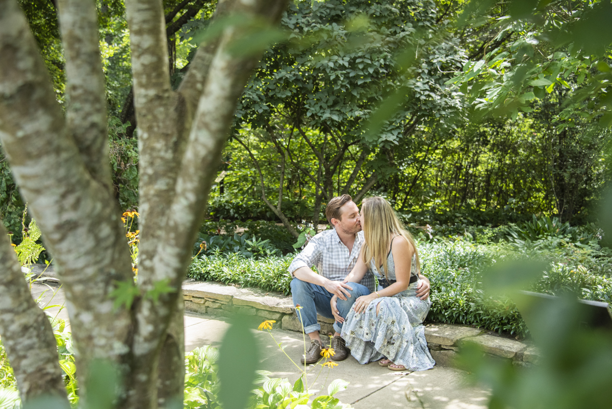 Couple kissing while sitting in garden after engagement