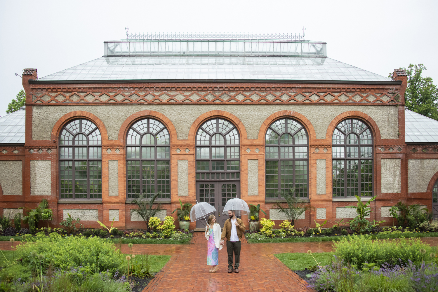 Couple under umbrellas standing in front of conservatory