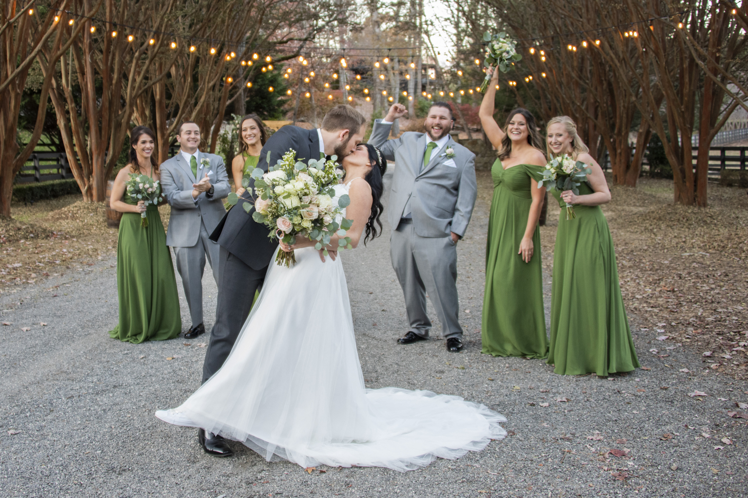 Couple kissing with wedding party behind them