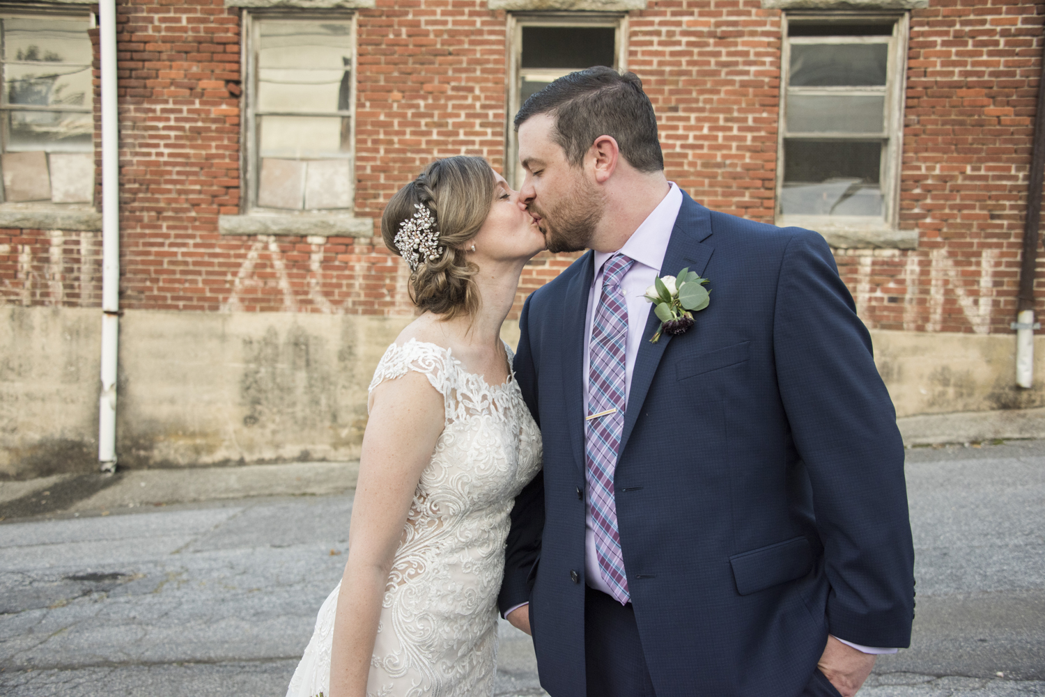 Couple kissing wedding portrait with vintage brick building in downtown Hendersonville, NC