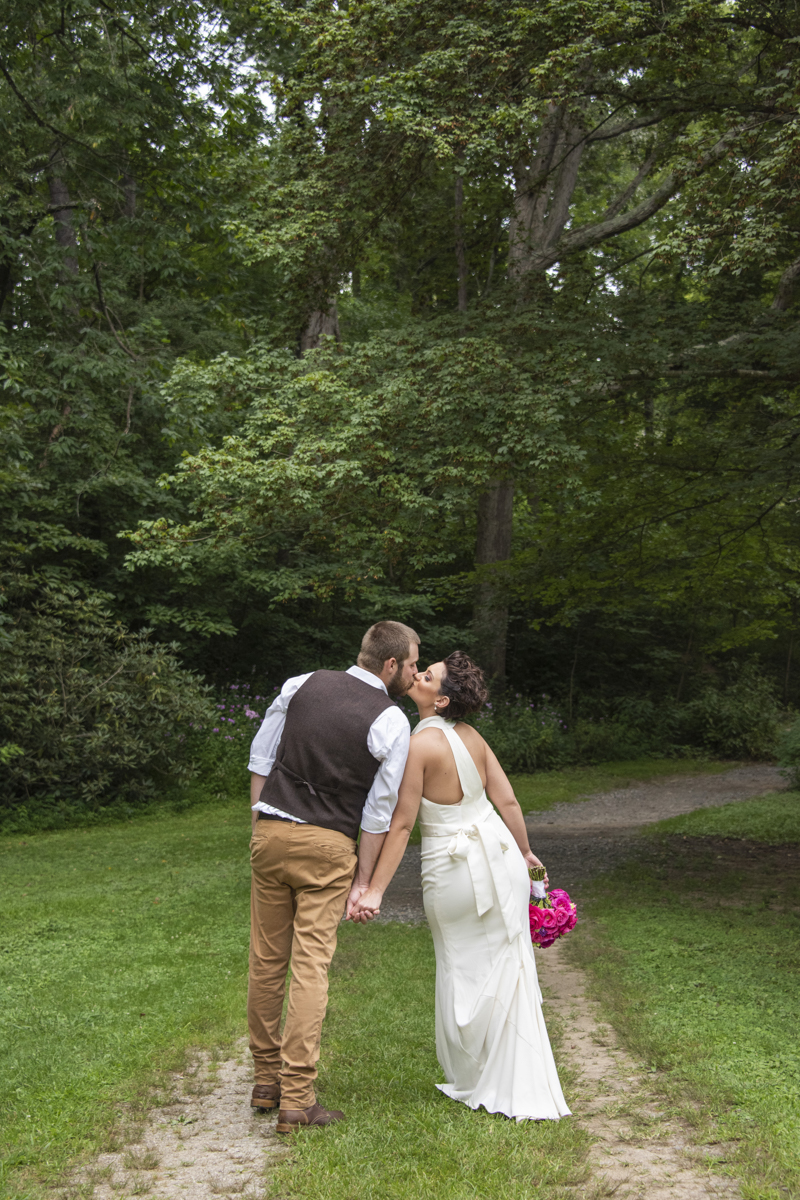 Couple walking away and kissing at Asheville Botanical Gardens elopement