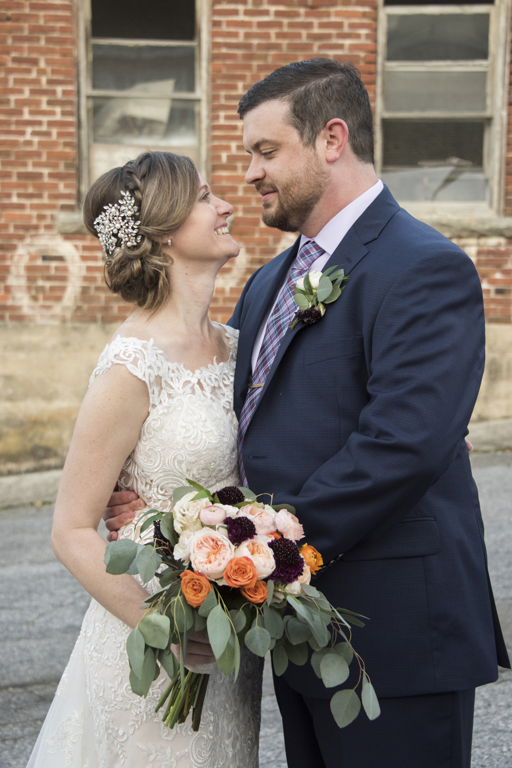 Couple looking at each other wedding portrait with vintage brick building in downtown Hendersonville, NC