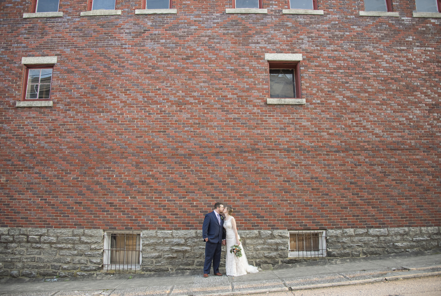 Couple kissing wedding portrait with vintage brick building in downtown Hendersonville, NC