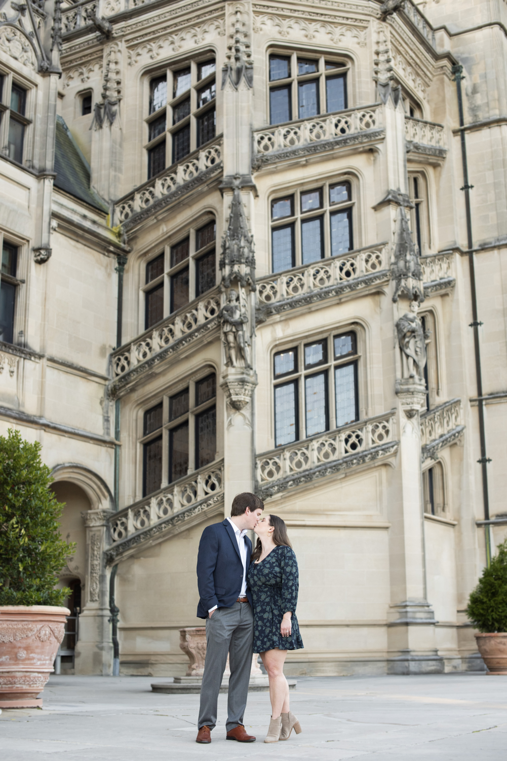 Couple kissing in front of grand staircase at Biltmore Estate fall engagement photography