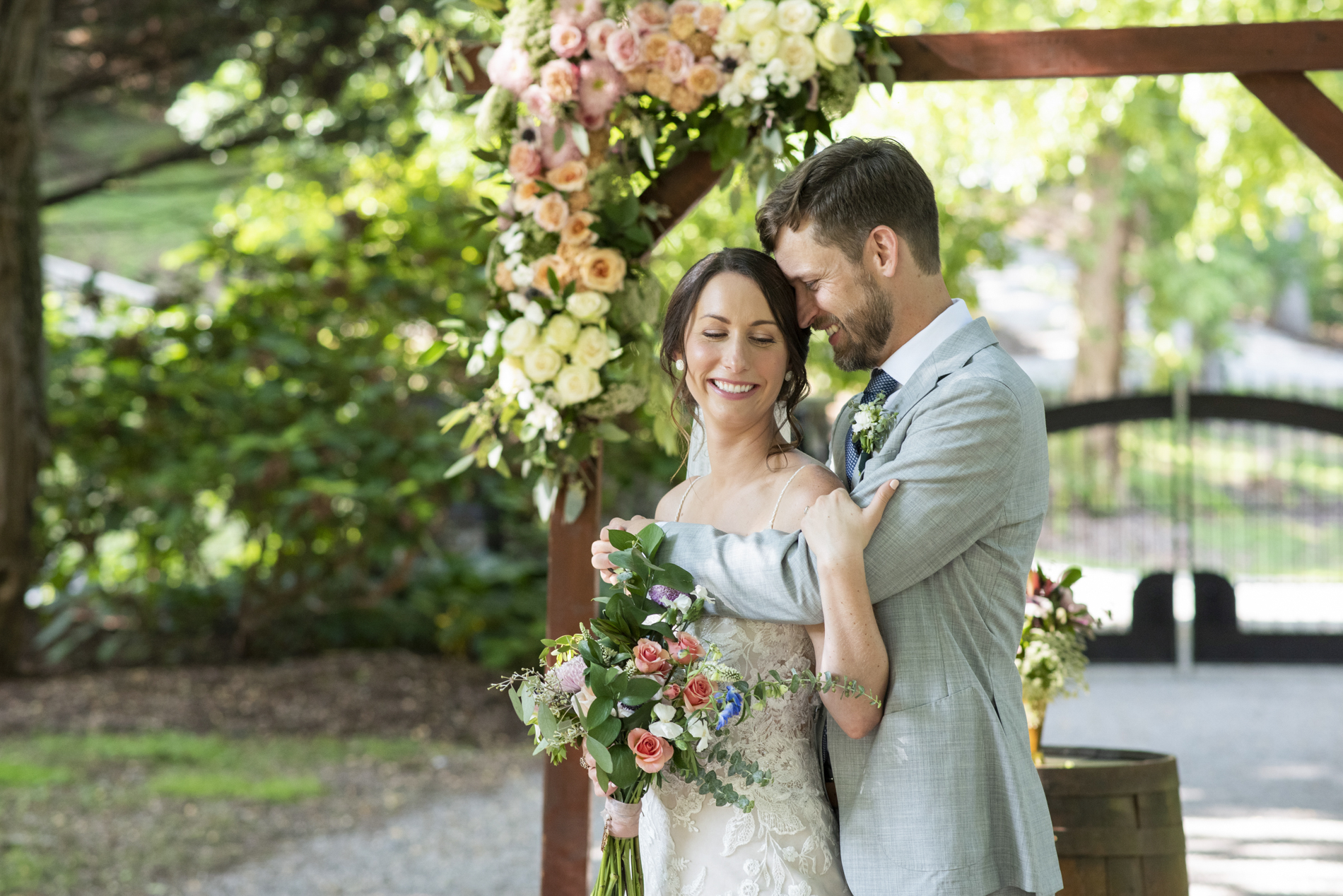 Couple snuggling at ceremony arbor with Hawkesdene Wedding Photographer