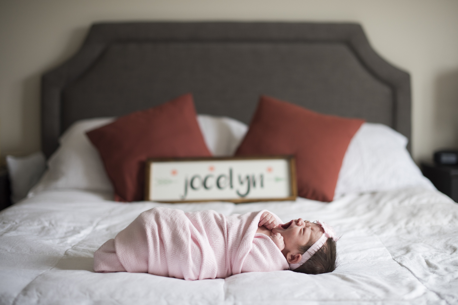 Baby girl yawning on bed in pink swaddle during Newborn Photography in Asheville