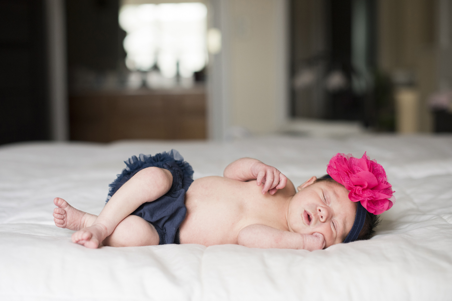 Newborn baby girl laying on side on bed during Newborn Photography in Asheville