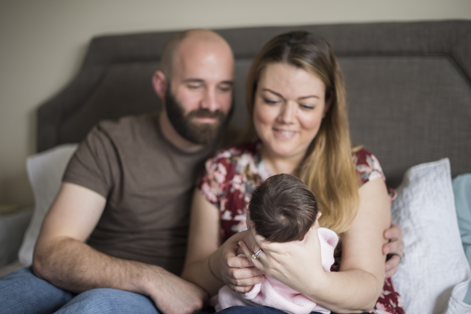 Parents holding baby girl while on their bed