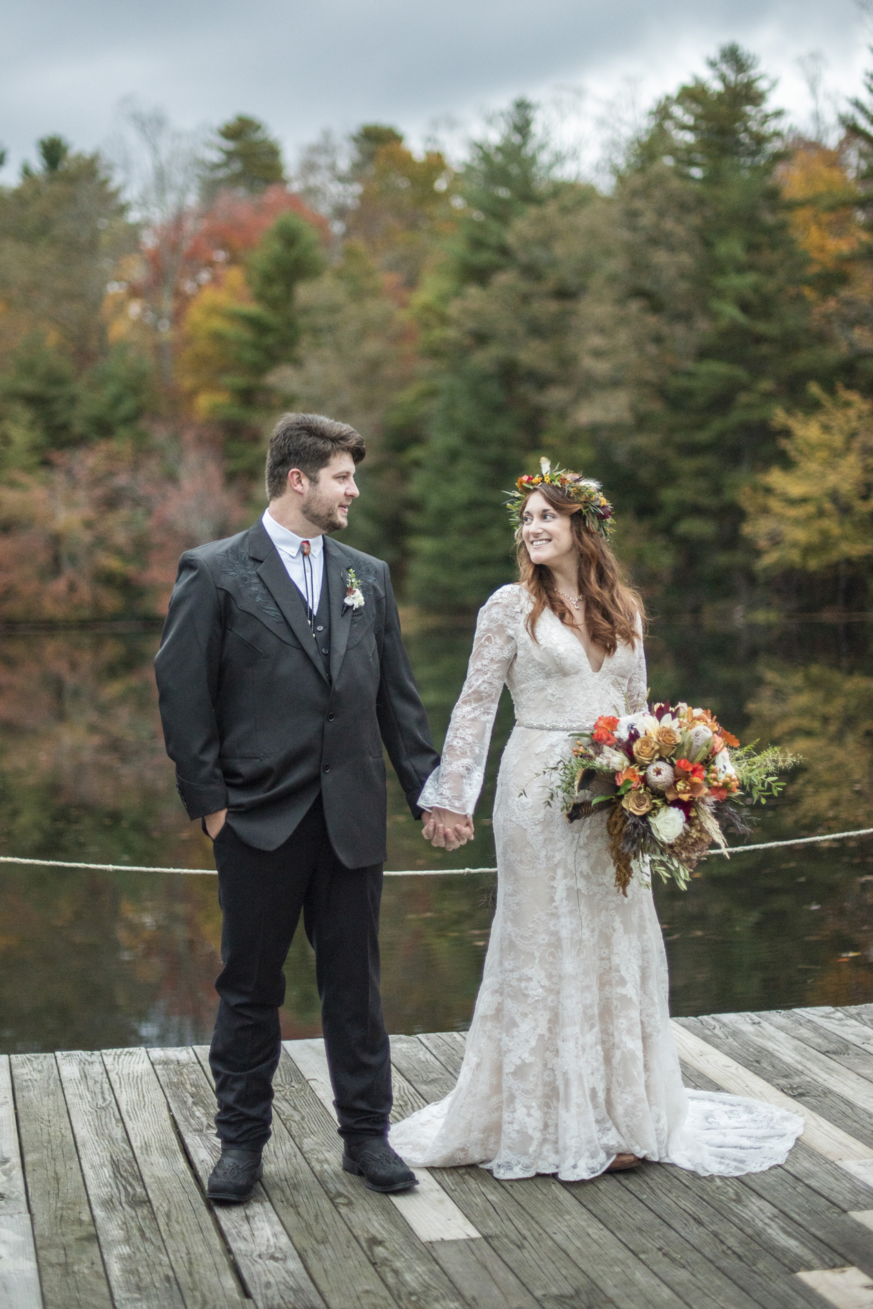 Couple holding hands on dock at Highland Lake Inn wedding during fall