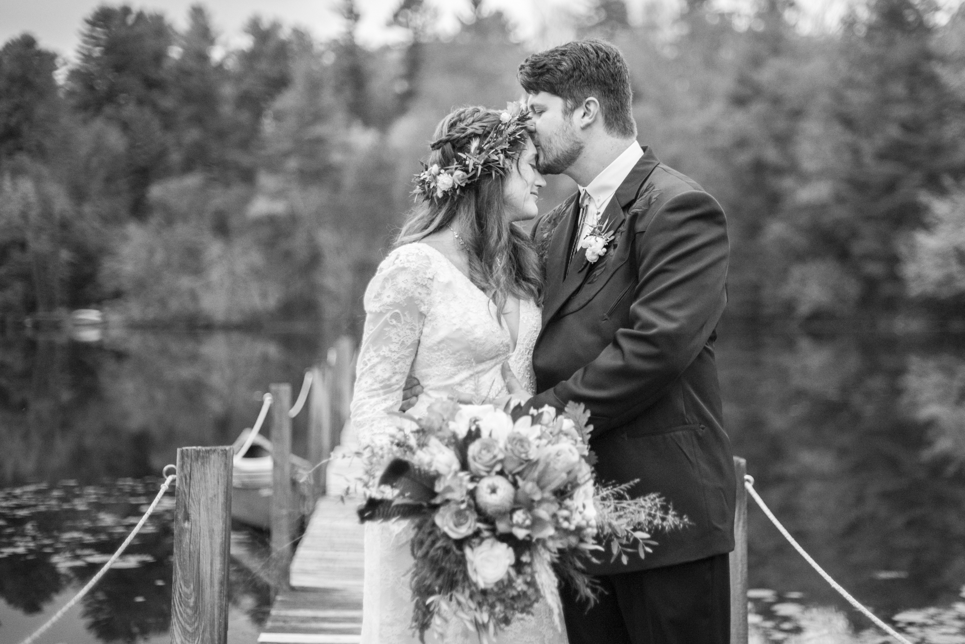 Groom kissing Bride on forehead at Highland Lake Inn wedding on dock