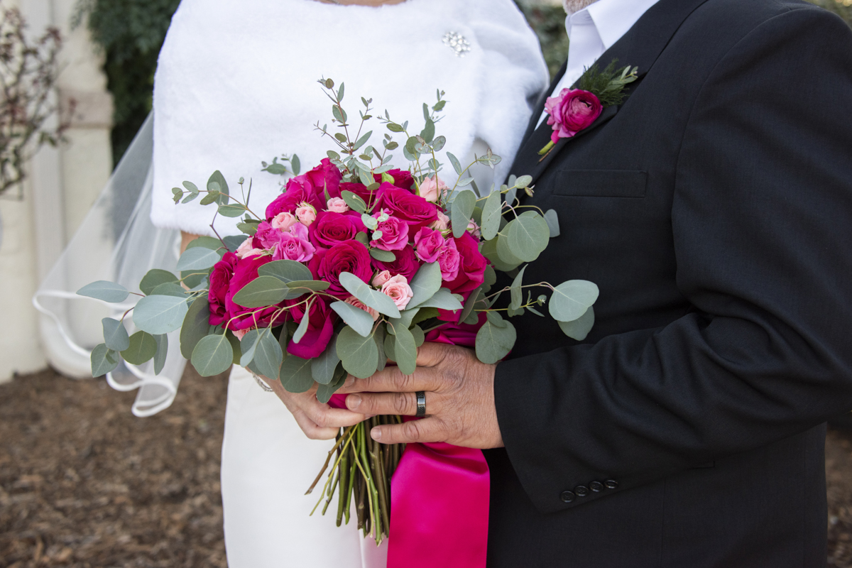 Couple holding bouquet with pink and red flowers in winter