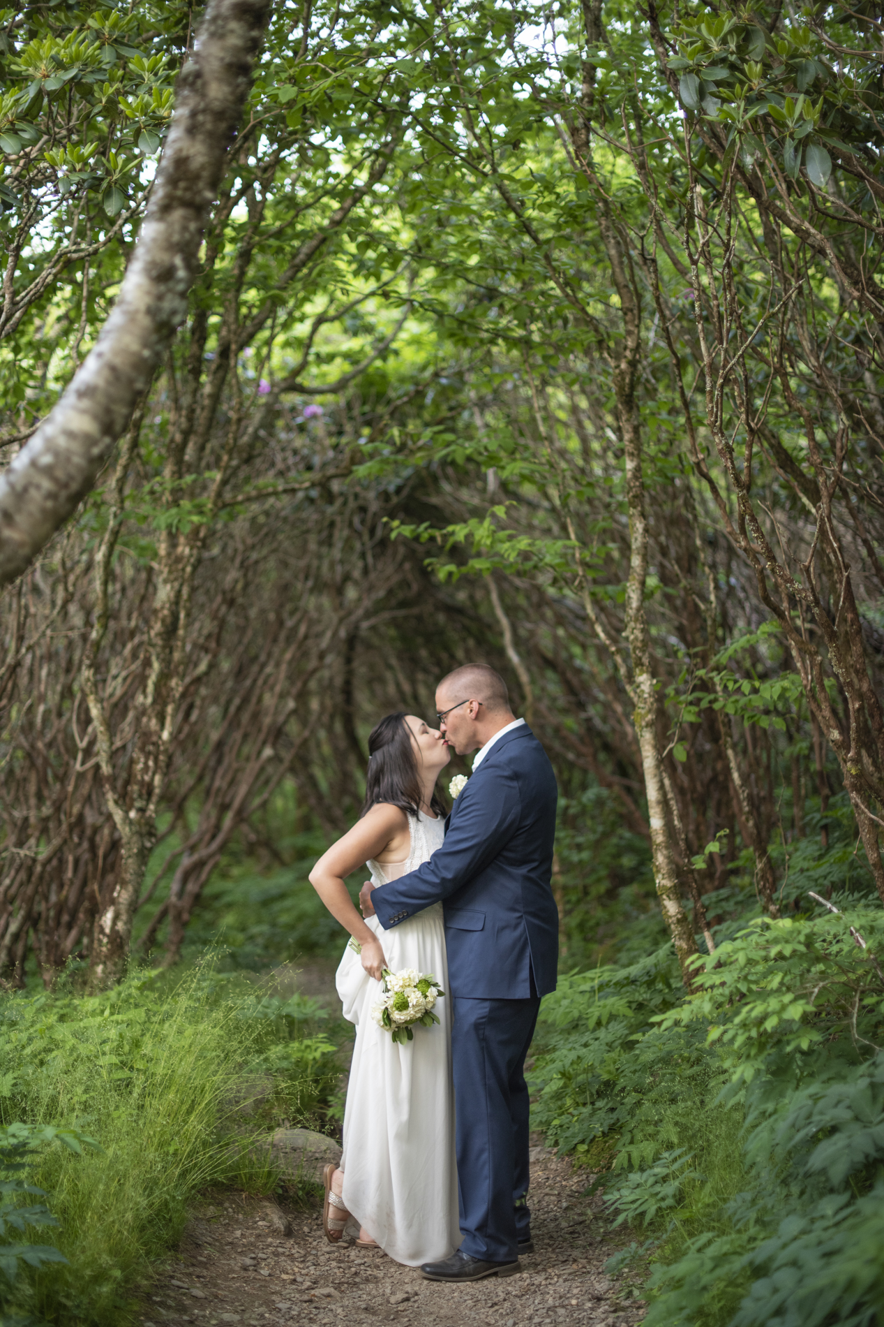 Couple kissing on hiking trail in woods at Craggy Gardens wedding