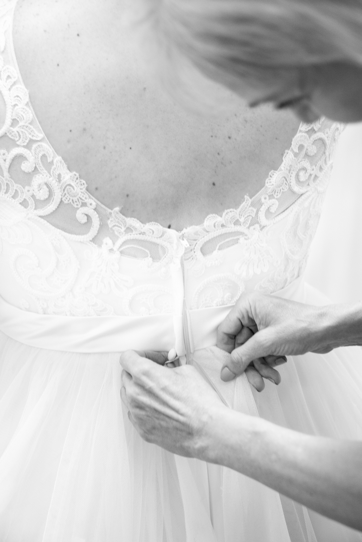 Mother buttoning bride's dress