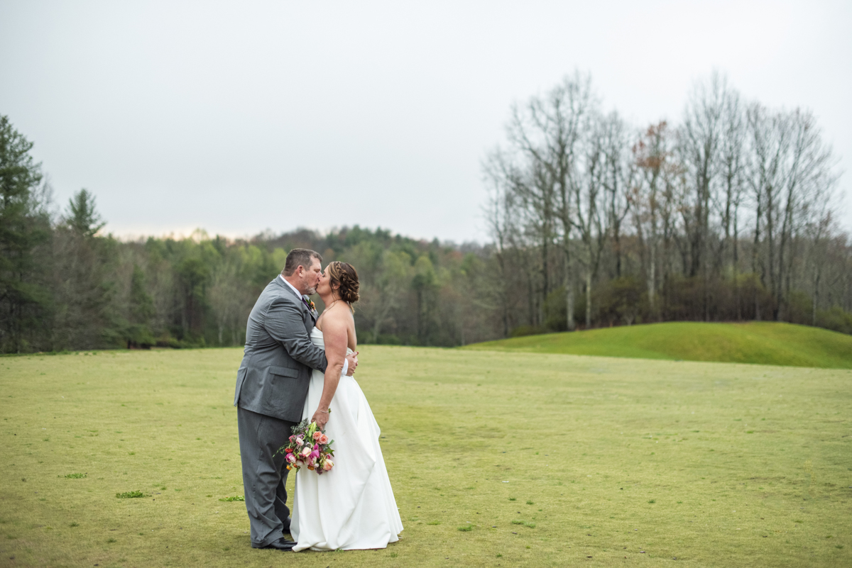 Couple kissing at Connestee Falls Wedding on golf green