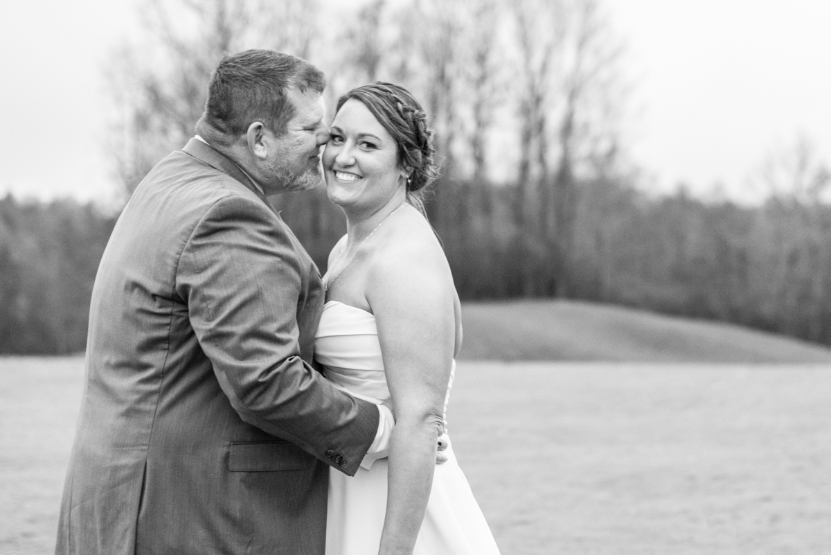 Couple snuggling at Connestee Falls Wedding on golf green