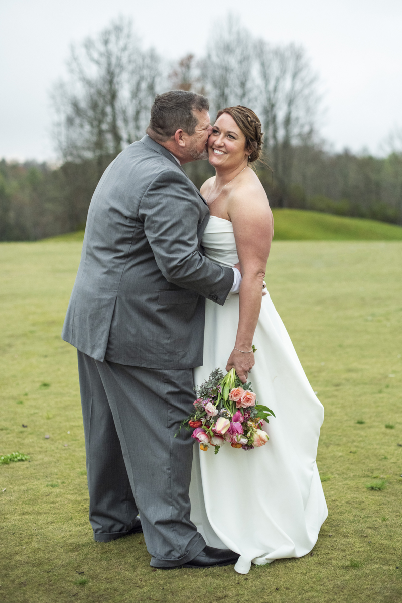 Groom kissing bride on cheek at Connestee Falls Wedding