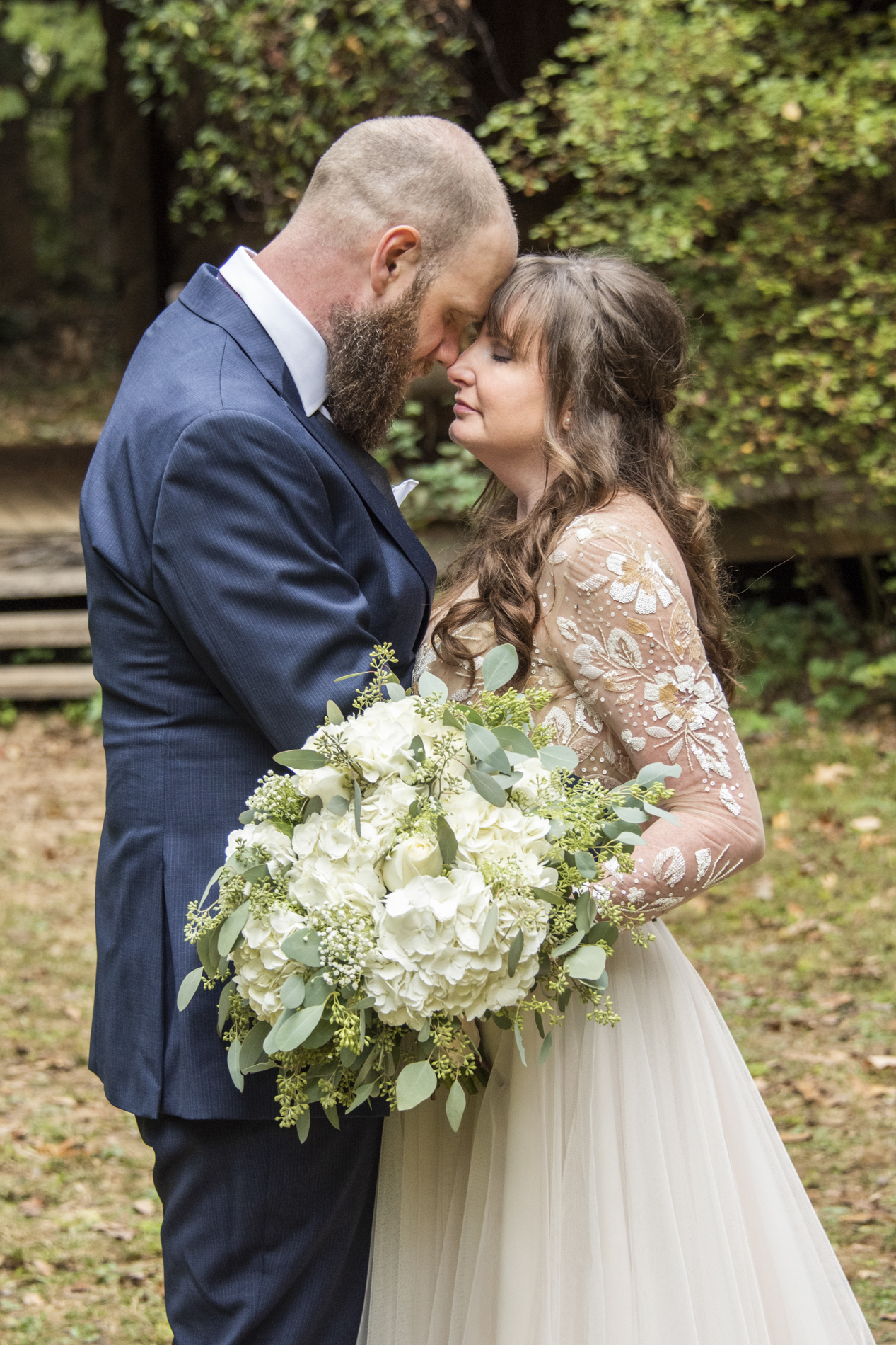 Couple snuggling at Asheville botanical gardens wedding