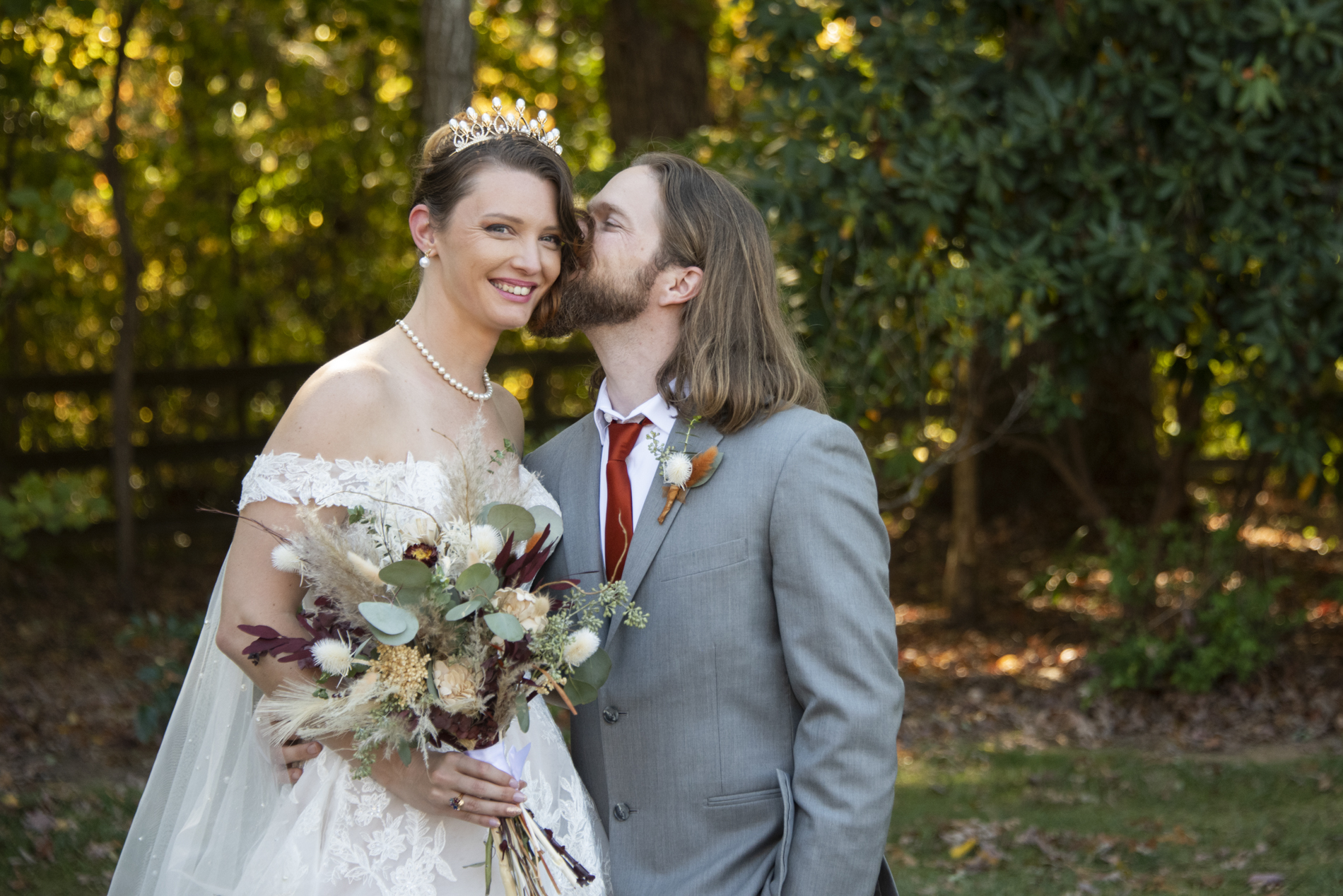 Groom kissing bride on cheek at The Farm Wedding Venue