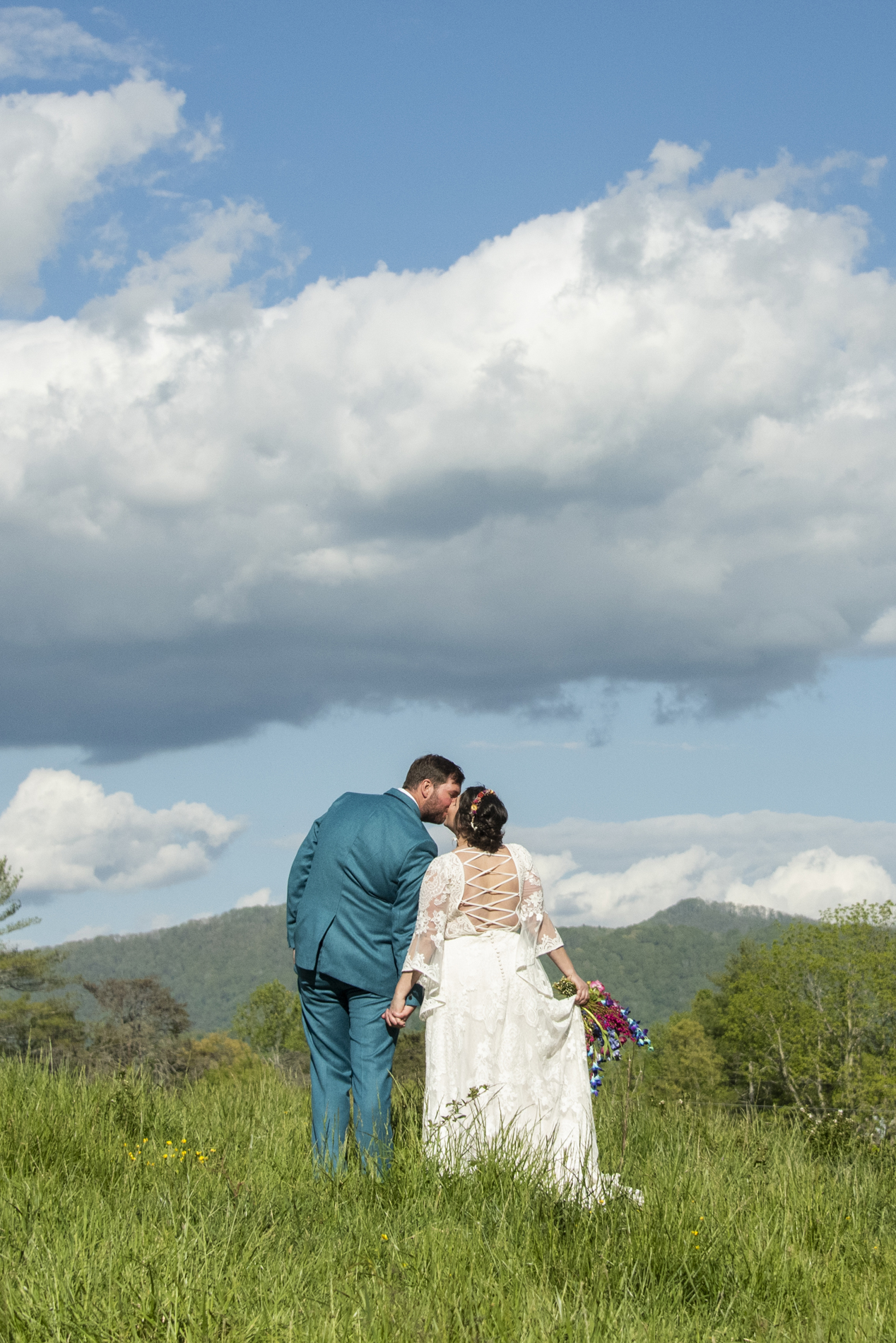 Couple kissing in field with mountains at Emerald Ridge Farm