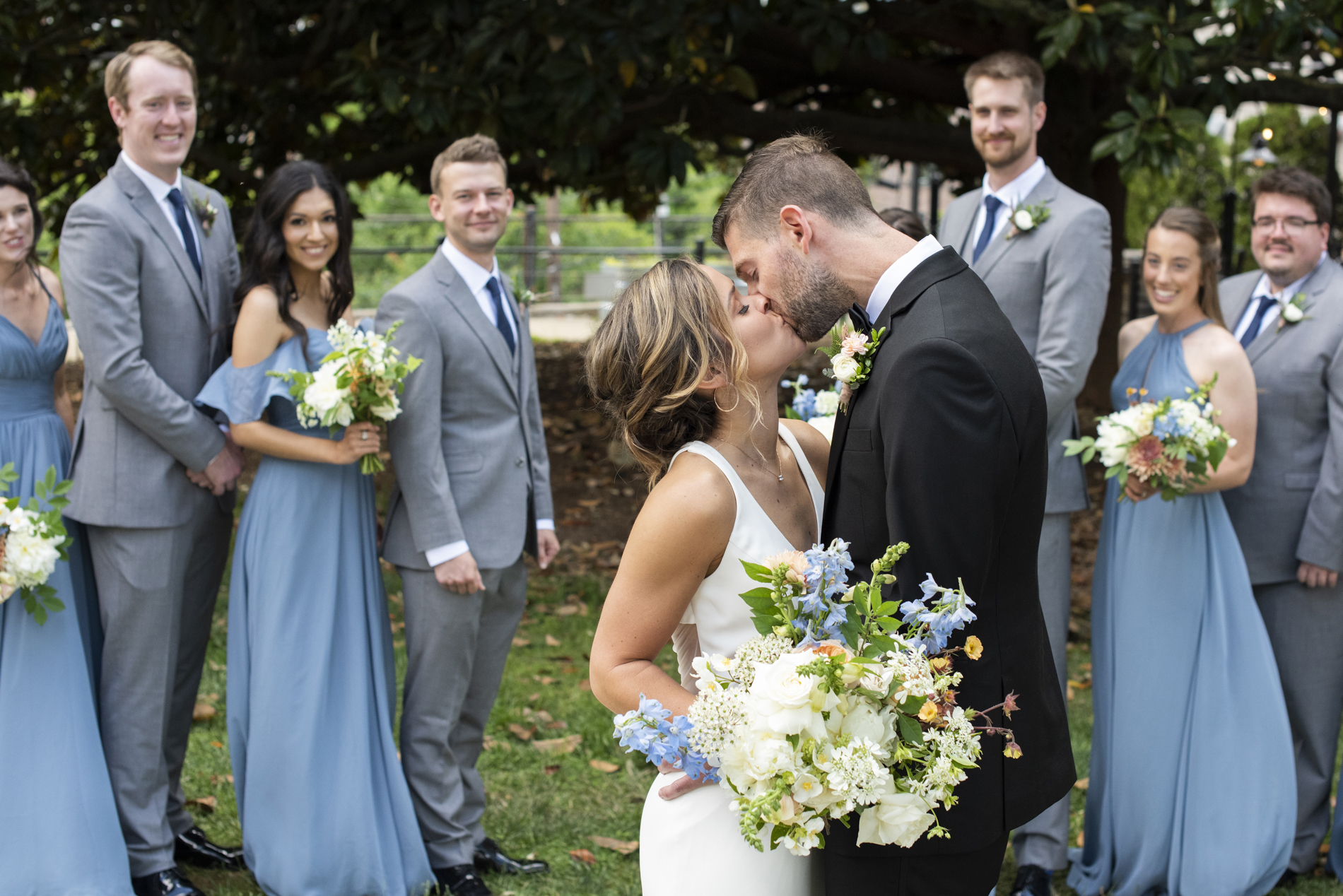Couple kissing in front of wedding party