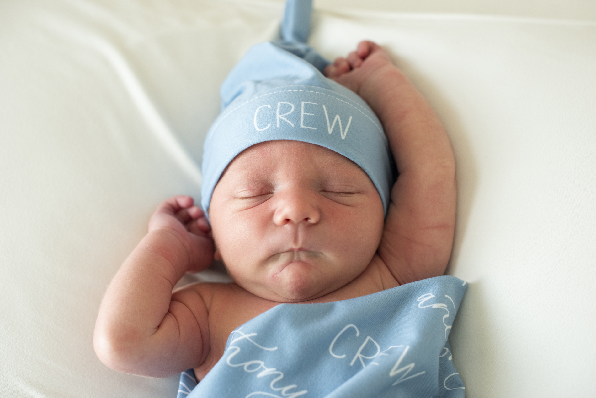 newborn baby with arms overhead