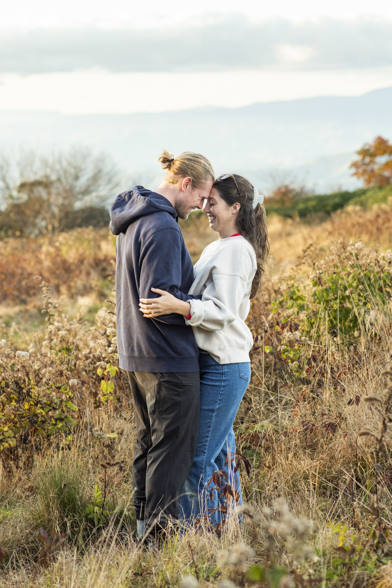 Couple snuggling on mountain top with Asheville proposal photographer