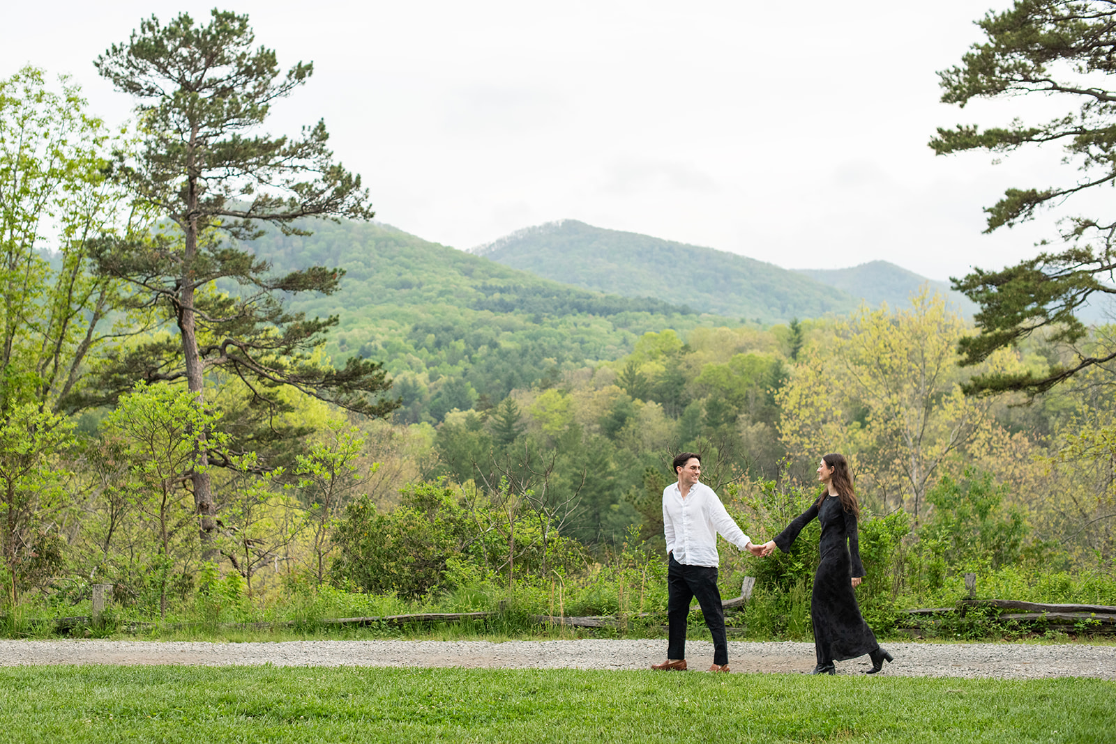 couple walking with mountains behind at NC Arboretum engagement