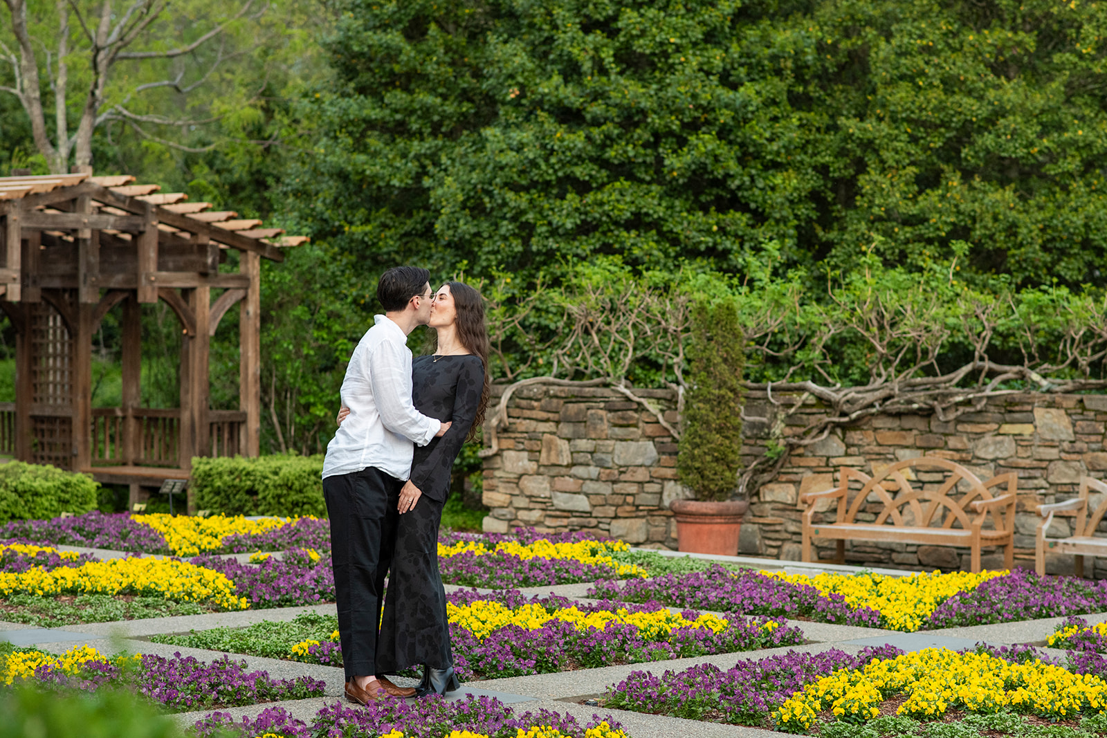 couple kissing in flower garden at NC Arboretum engagement