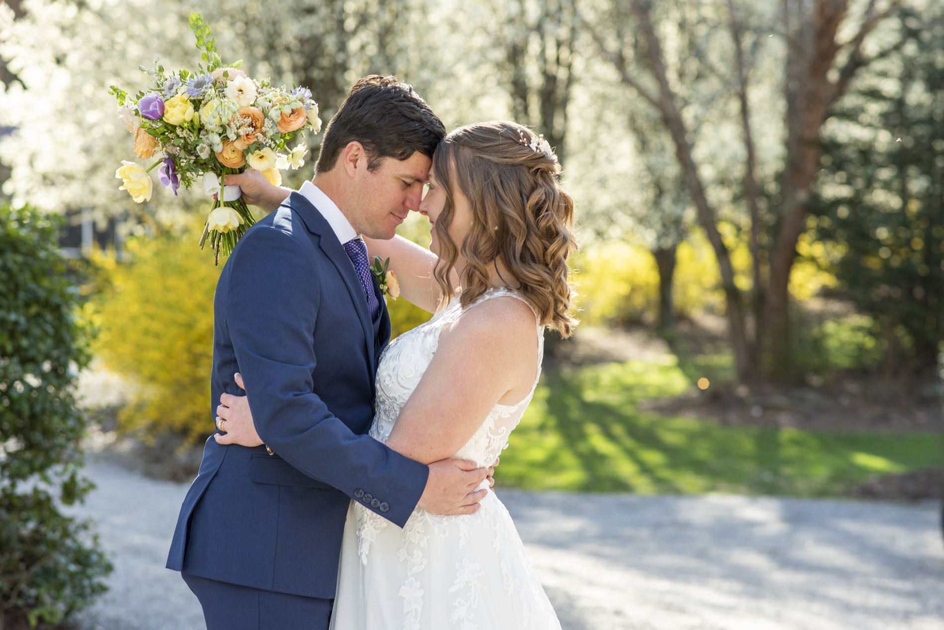 Couple snuggling with spring flowers behind at Hawkesdene wedding venue